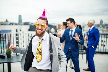 Eine große Gruppe fröhlicher Geschäftsleute feiert eine Party auf der Dachterrasse in der Stadt. - HPIF18313