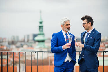 Zwei Geschäftsleute mit Champagner im Freien auf einer Dachterrasse in der Stadt. - HPIF18319