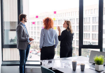 Eine Gruppe junger Geschäftsleute, die sich in einem Büro unterhalten und ein Brainstorming durchführen. - HPIF18388