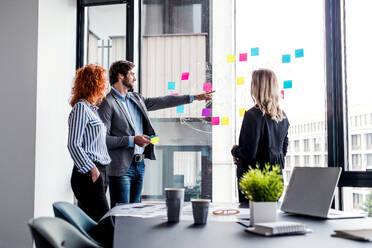 A group of young business people talking in an office, brainstorming. - HPIF18389