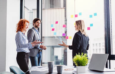 Eine Gruppe junger Geschäftsleute, die sich in einem Büro unterhalten und ein Brainstorming durchführen. - HPIF18390