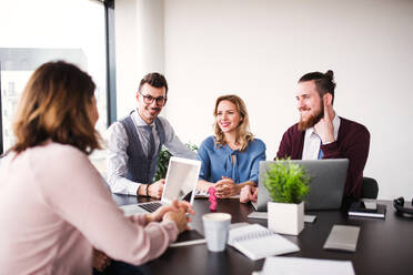 Eine Gruppe junger Geschäftsleute sitzt in einem Büro und unterhält sich bei einer Besprechung. - HPIF18407