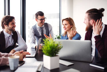 Eine Gruppe junger Geschäftsleute sitzt in einem Büro und unterhält sich bei einer Besprechung. - HPIF18409