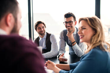 Eine Gruppe junger Geschäftsleute sitzt in einem Büro und unterhält sich bei einer Besprechung. - HPIF18415