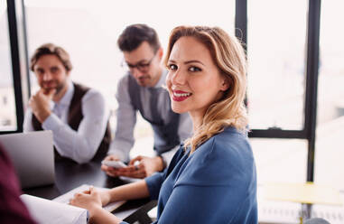 Eine Gruppe junger, fröhlicher Geschäftsleute mit Laptop sitzt in einem Büro und unterhält sich. - HPIF18416