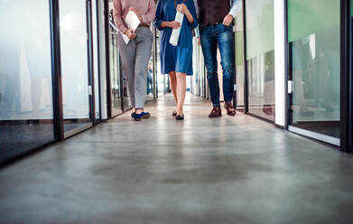 A midsection of group of business people walking in corridor office building. Copy space. - HPIF18456