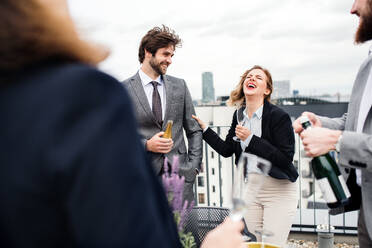 A large group of joyful businesspeople having a party outdoors on roof terrace in city. - HPIF18458