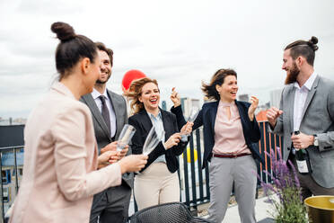 Eine große Gruppe fröhlicher Geschäftsleute feiert eine Party auf der Dachterrasse in der Stadt. - HPIF18460