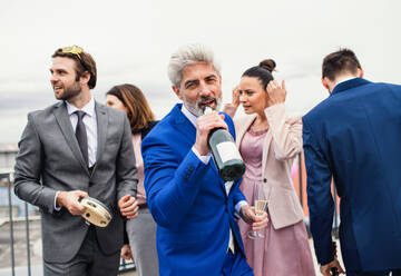 Eine große Gruppe fröhlicher Geschäftsleute feiert eine Party auf der Dachterrasse in der Stadt. - HPIF18472