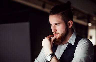 A portrait of young businessman in an office at night, working. Copy space. - HPIF18503