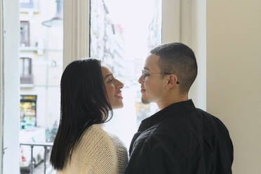 Smiling couple looking at each other near window at home - SOBF00005