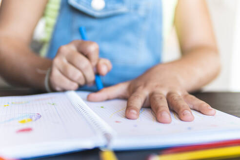 Mädchen zeichnet Hand auf Notizbuch mit Buntstift - JAQF01227