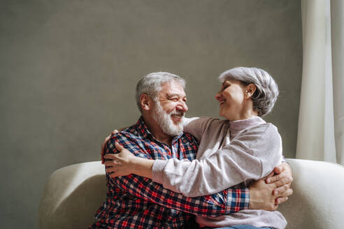 Romantic mature couple embracing on couch at home - MDOF01124