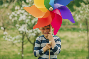 Happy boy with pinwheel toy standing in garden - VSNF00911