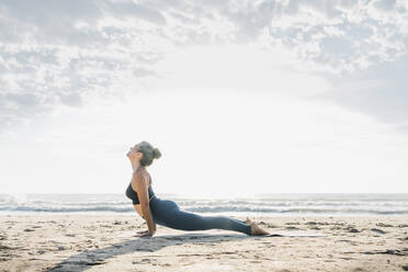 Frau übt Kobra-Pose am Strand - AAZF00560