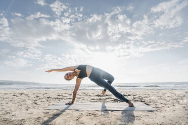 Frau übt Camatkarasana am Strand - AAZF00563