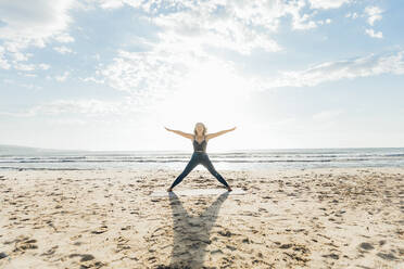 Frau übt Yoga mit ausgestreckten Armen an einem sonnigen Tag - AAZF00568