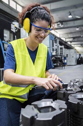 Smiling engineer wearing reflective clothing working in modern factory - AAZF00598