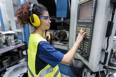 Ingenieur in Arbeitsschutzkleidung bei der Bedienung einer CNC-Maschine in einer modernen Fabrik - AAZF00605