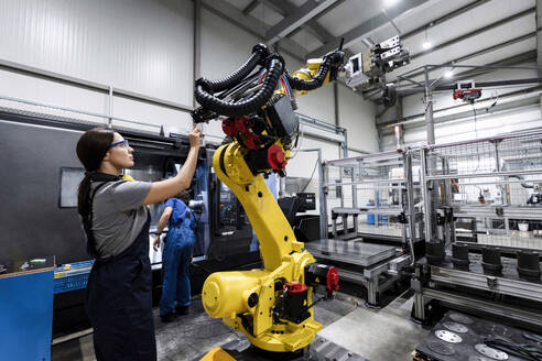 Wartungsingenieur bei der Arbeit in einer Fabrik mit einem Roboterarm - AAZF00608