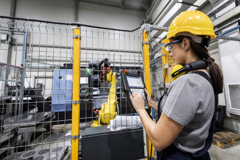 Ingenieur, der einen Roboterarm in einer modernen Fabrik bedient - AAZF00613