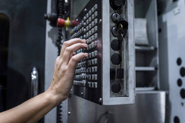 Hand eines Wartungstechnikers, der eine CNC-Maschine in einer modernen Fabrik bedient - AAZF00628