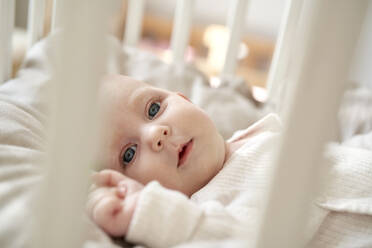 Baby girl with gray eyes lying in crib at home - ABIF01989