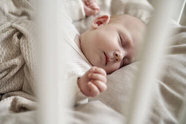 Baby girl with eyes closed sleeping in crib - ABIF01994