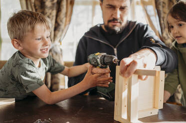 Sohn hilft Vater beim Bau eines Vogelhauses zu Hause - ANAF01439