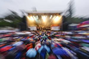 Überfülltes Musikfestival mit Publikum, das Regenschirme trägt - MAMF02858