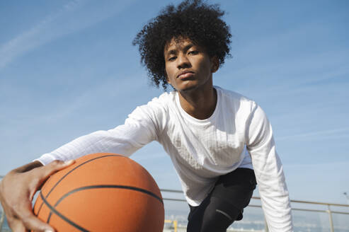 Selbstbewusste Sportlerin mit lockigem Haar beim Basketballspielen - ALKF00290