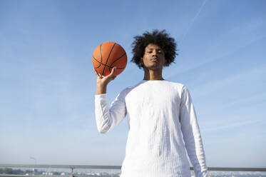 Sportler hält Basketball vor dem Himmel - ALKF00292