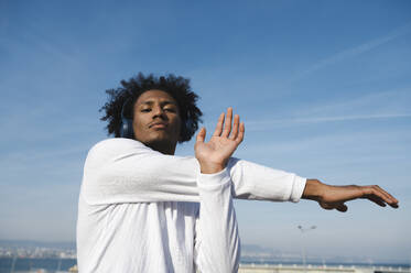 Athlete with bluetooth headphones exercising at sunny day - ALKF00298