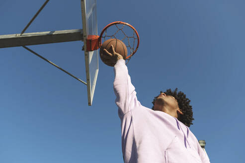 Ein Sportler fängt einen Basketball unter einem Basketballkorb auf einem Sportplatz - ALKF00317