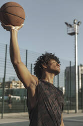 Athlete holding basketball in hand at sports court - ALKF00321