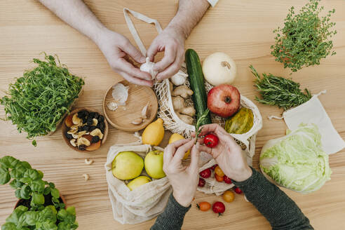 Hände eines Paares mit Obst und Gemüse auf einem Tisch zu Hause - YTF00838