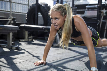 Frau macht Push-up-Übung auf dem Dach eines Fitnessstudios - IKF00669