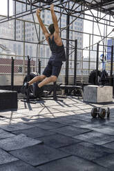 Mann macht Calisthenics auf dem Dach eines Fitnessstudios - IKF00673