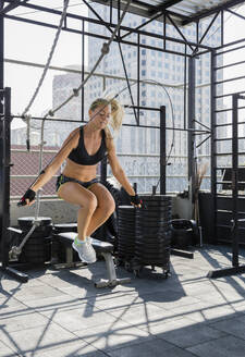 Frau springt Seil auf dem Dach eines Fitnessstudios - IKF00678
