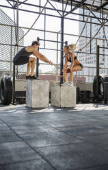 Friends practicing box jumping at rooftop gym - IKF00680