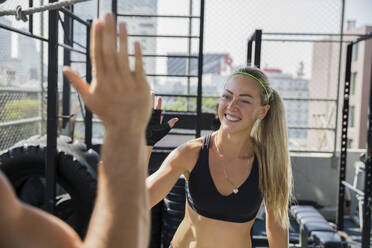 Happy friends giving high-five at rooftop gym - IKF00684