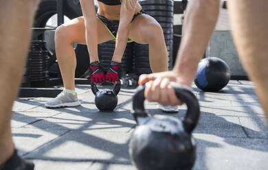 Friends exercising with kettlebells at rooftop gym - IKF00691