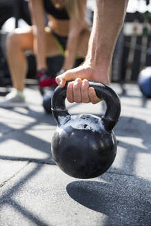 Mann trainiert mit Kettlebell auf dem Dach eines Fitnessstudios - IKF00693