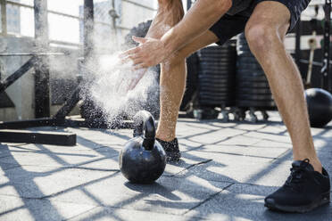 Mann, der Sportkreide abstaubt, trainiert im Fitnessstudio auf dem Dach - IKF00694