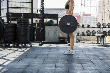 Woman lifting weights at rooftop gym - IKF00701