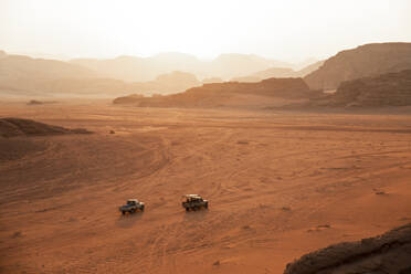 Autos auf unbefestigter Straße in der Wüste bei Sonnenuntergang - PCLF00563