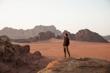 Mann steht bei Sonnenuntergang auf einem Wüstenfelsen - PCLF00565