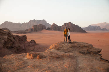 Couple standing on rock in desert at sunset - PCLF00566
