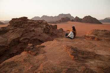 Loving couple sitting on rock in desert - PCLF00573