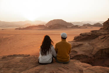Couple sitting on rock and looking at sunset - PCLF00575